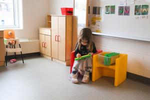 kinder girl drawing in a play kitchen
