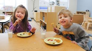 Two preschoolers eating lunch and smiling