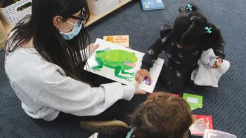 child and teacher reading a picture book