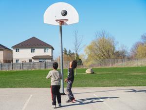 two school age boys playing basketball
