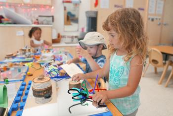 3 preschoolers playing with loose parts