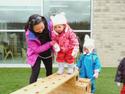 educator helping a toddler climb a wooden obstacle
