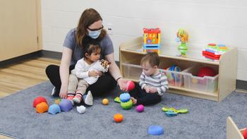 Educator and infants playing with toys.