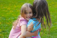school age girl giving a kinder age girl a piggy back ride.