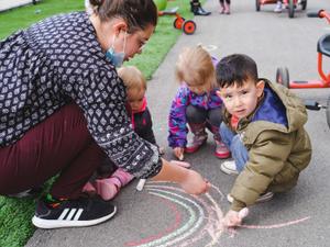 toddlers and educator with drawing a rainbow with chalk