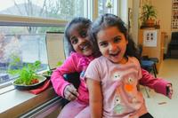 two little girls laughing together in front of a window