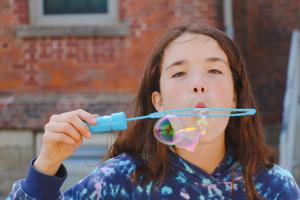 school age girl blowing bubbles