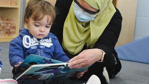 Toddler and educator reading a book