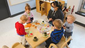 toddlers have a play lunch in a toy kitchen with educator