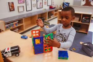 preschool boy making a house with toys