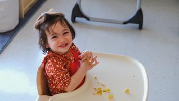 infant girl smiling with snack