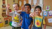 three school age boys smiling and waving