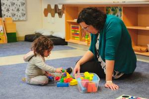 educator and toddler playing with blocks.