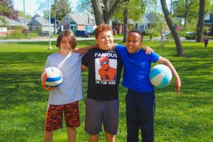 three school age boys with volley balls